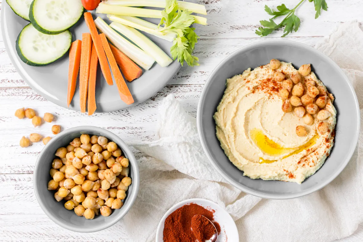 طبق حمص مع حبات حمص وخضار من الأعلى، والحمص غني بالكربوهيدرات